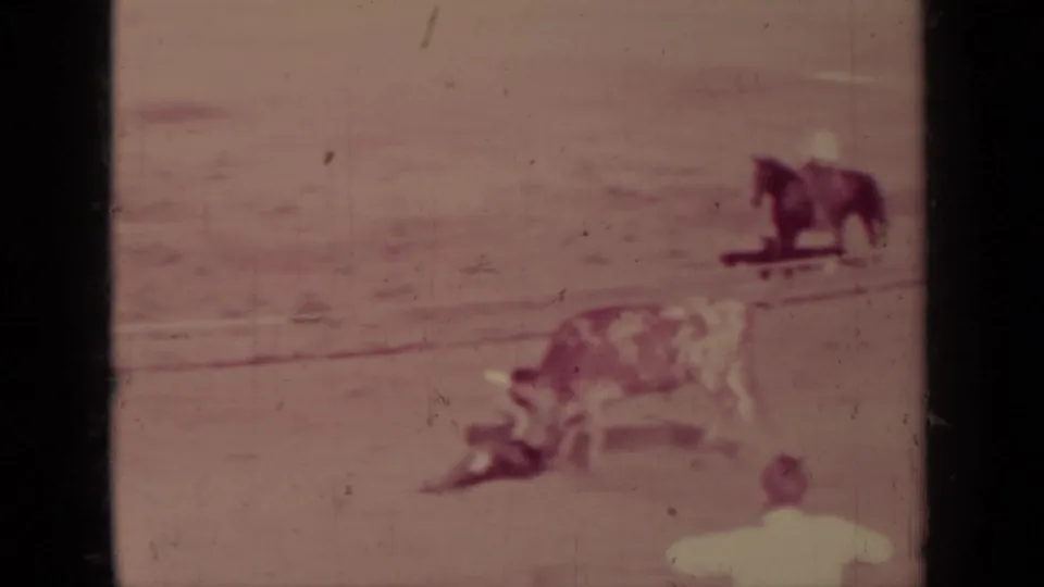 1937 Klamath rodeo frame with a bull in the foreground, a horseback rider at right, and a distant person near the arena edge.