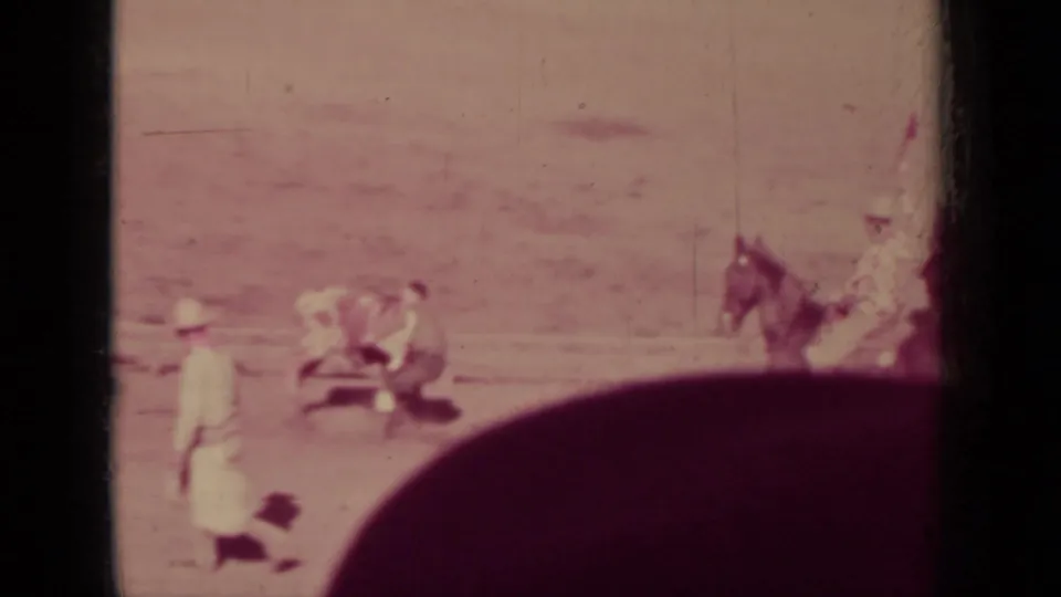 Klamath, California 1937 frame with cowboys around a bull or steer in a dusty arena and a horse rider nearby.