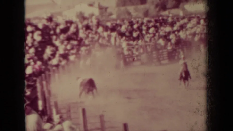 1937 Klamath rodeo frame with a mounted rider pursuing livestock through dust while spectators watch from the bleachers.