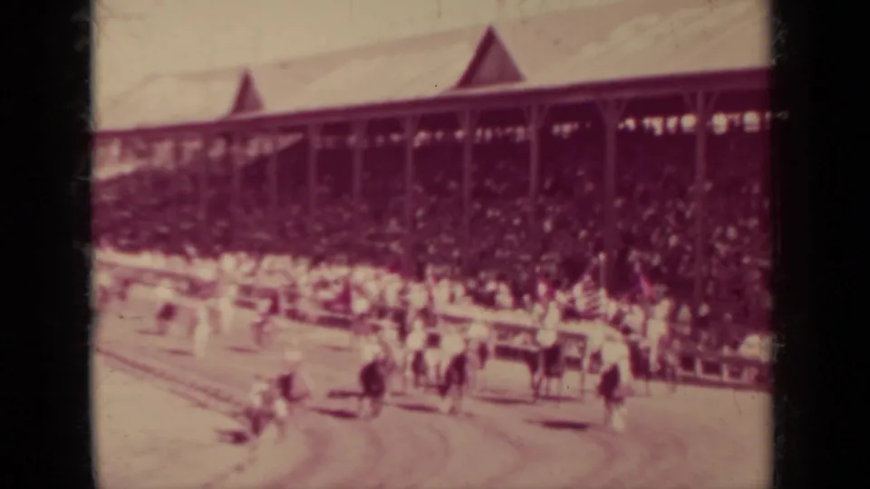 Wide 1937 Klamath racetrack view with horses, riders, railings, and a large crowd seated under the grandstand roof.
