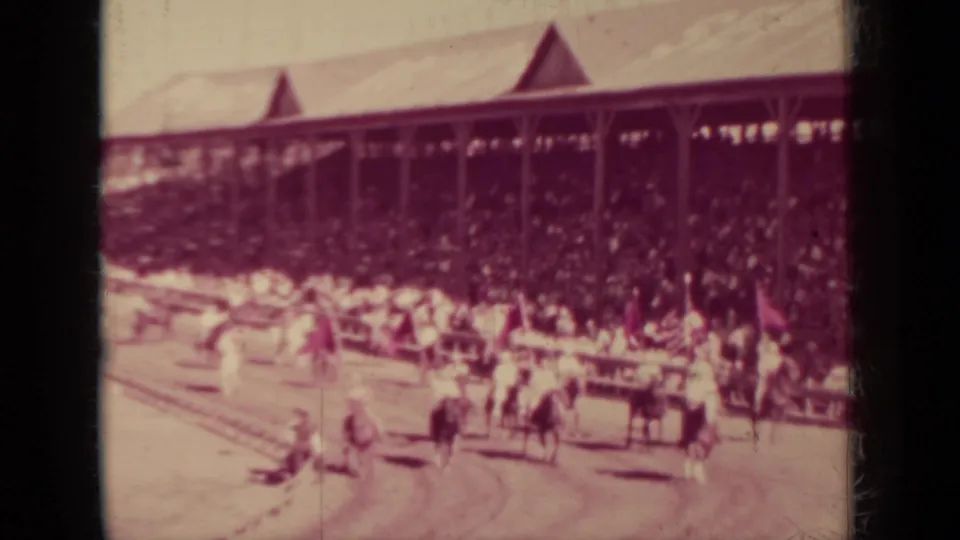 Late clip frame from the 1937 Klamath race event showing horses near the rail and a dense grandstand crowd behind them.