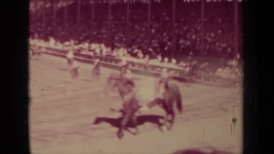 A closer 8mm frame shows mounted riders moving past the camera with a crowded public viewing area behind them.