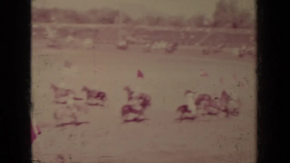 1937 Klamath, California home-movie frame showing distant mounted riders in an outdoor arena with spectators in the background.