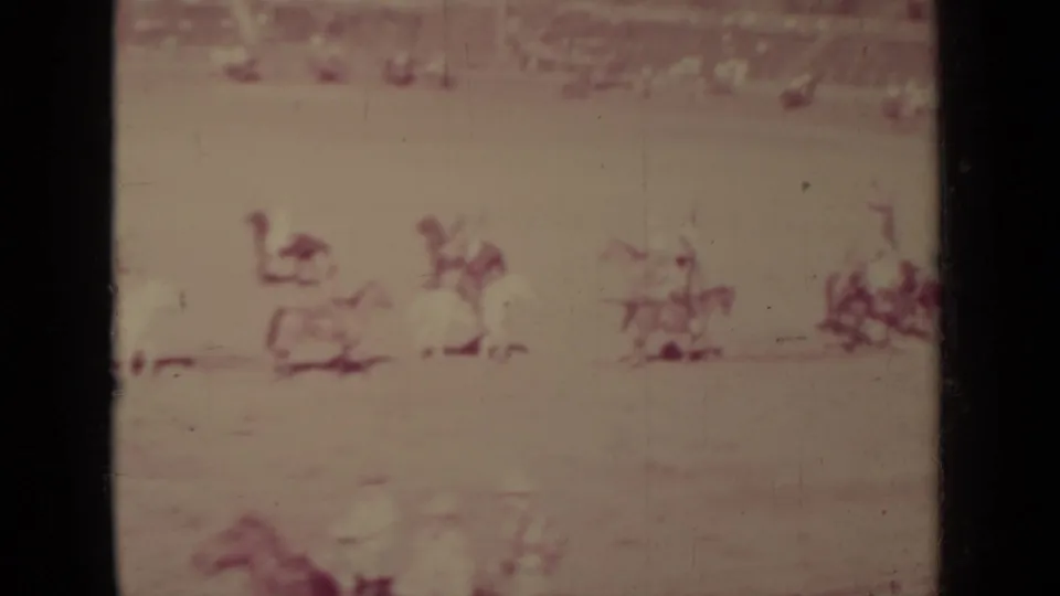 1937 Klamath home-movie frame showing multiple distant riders spread across a dusty outdoor arena before spectators.