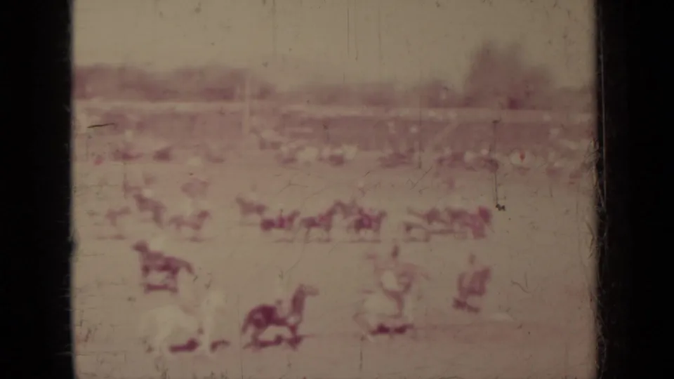 Wide 1937 Klamath arena view with distant horseback riders, a spectator line, and trees beyond the field.