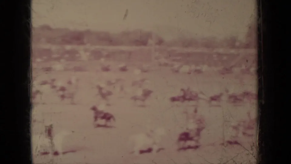 1937 Klamath, California 8mm frame showing distant horseback activity in an open field, softened by faded film and scratches.