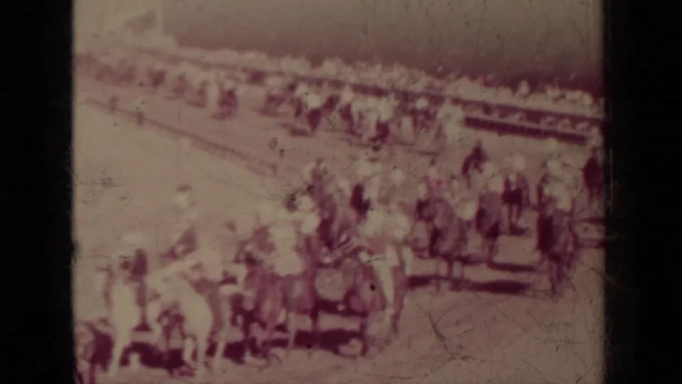 1937 Klamath, California home-movie frame with mounted riders gathered near a boundary as spectators watch from behind.