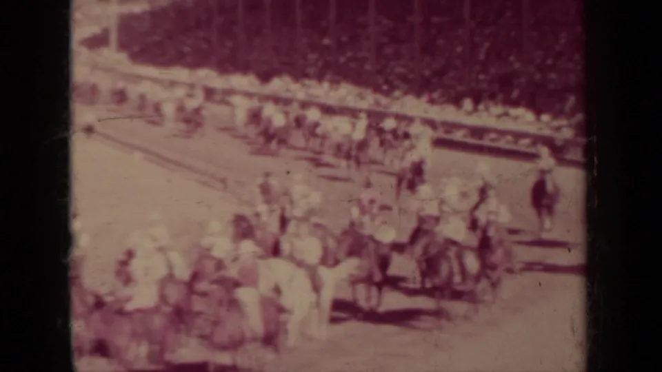 Faded 8mm frame from 1937 Klamath, California showing riders and horses moving through a field during a public outdoor gathering.