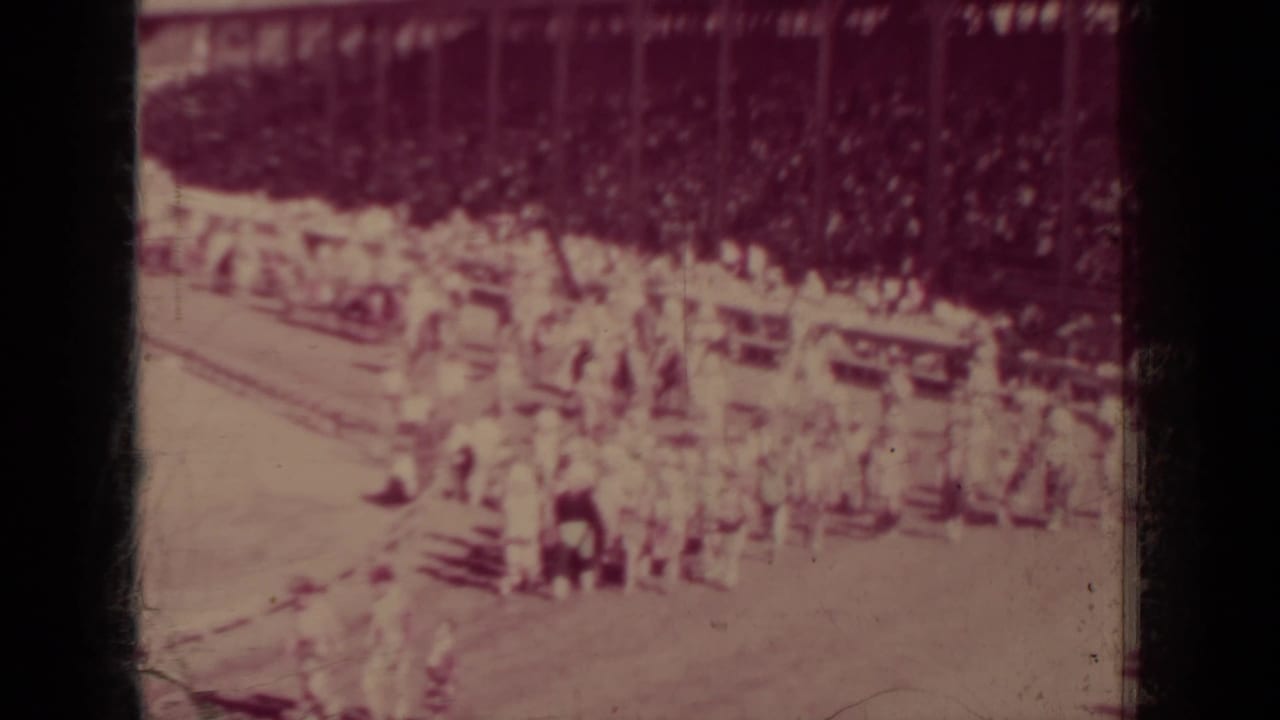 1937 Klamath event frame with a packed wooden grandstand and people clustered near the dirt racing track.