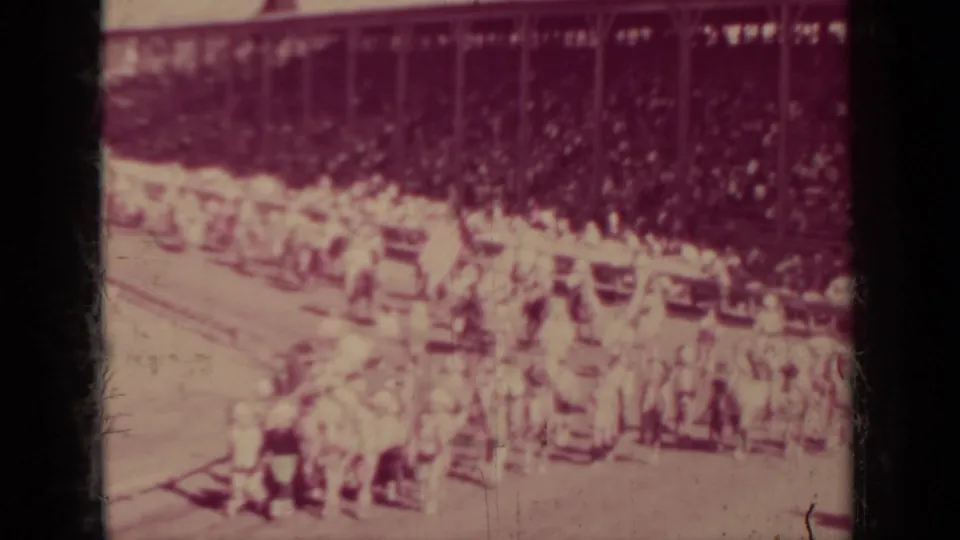 Distant 1937 Klamath parade view with marchers, possible flags, horseback riders, and spectators seated in background bleachers.