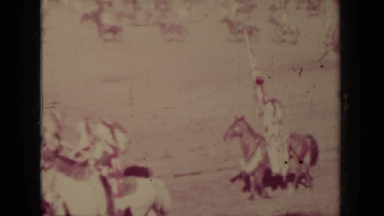 Distant horseback riders in a parade, with flags and figures in traditional clothing visible through faded film.