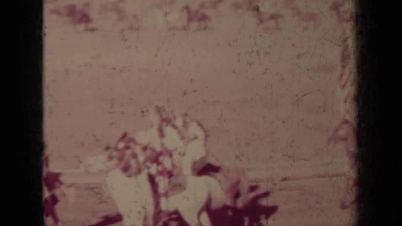 1937 Klamath, California 8mm frame of Indigenous riders on horseback carrying flags during a public parade.