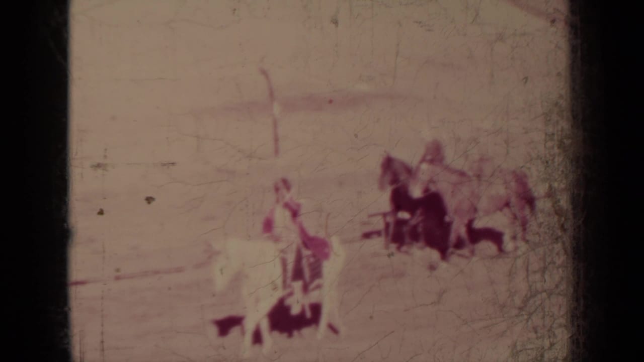 The faded 8mm frame shows people with horses during the Klamath, California parade sequence, with details softened by exposure and film wear.
