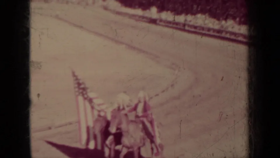 A Klamath, California parade frame shows horses and people near multiple flags, with a curved dirt track visible in the background.