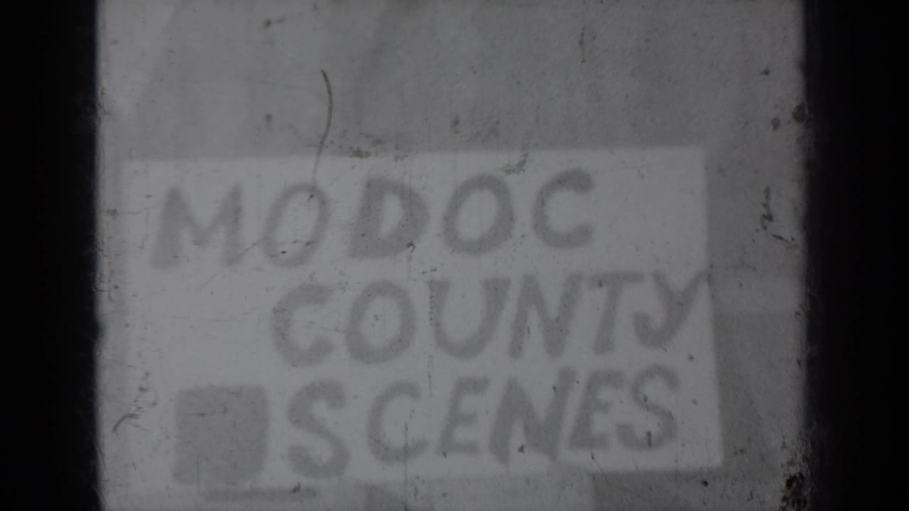 Soft, worn 8mm frame showing the “MODOC COUNTY SCENES” title card, with scratches and low contrast across the image.