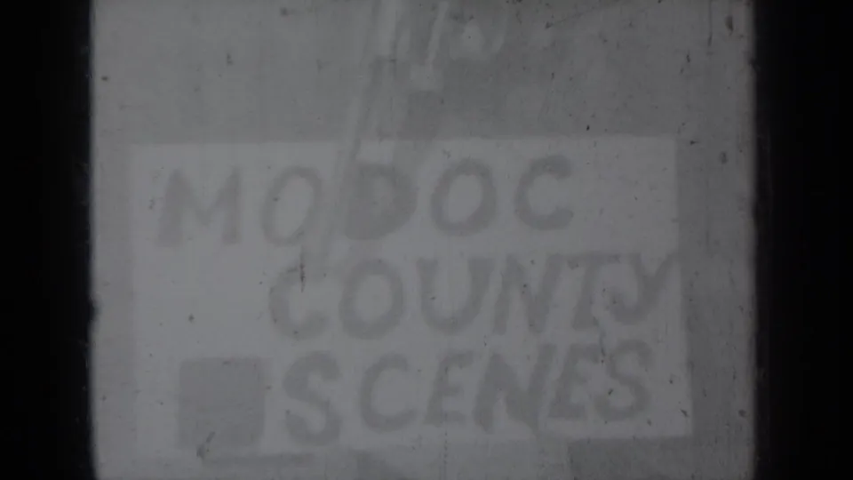 Final faded frame of the hand-lettered Modoc County title card, with heavy grain, scratches, and dark film edges.