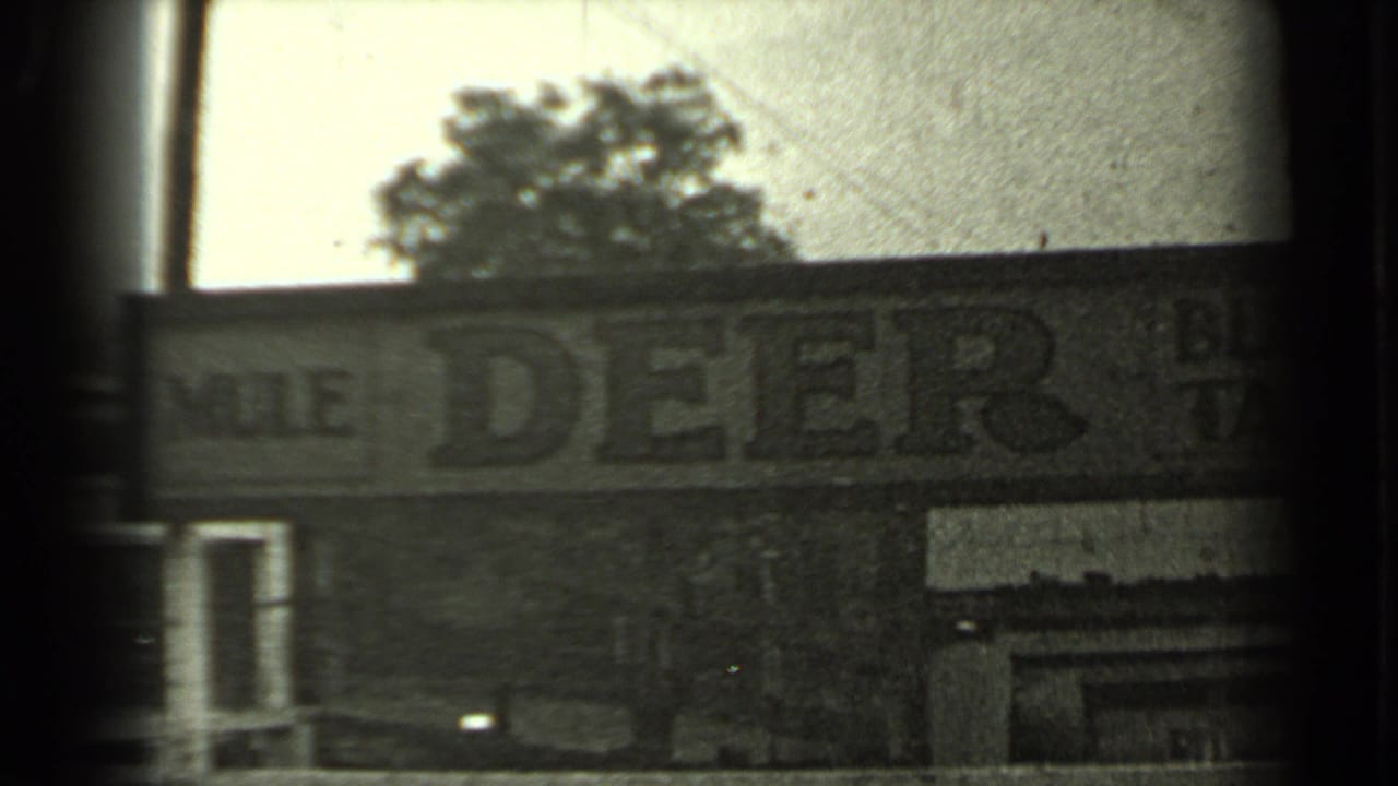 Roadside Mule Deer Bar sign seen through dark film-frame edges.
