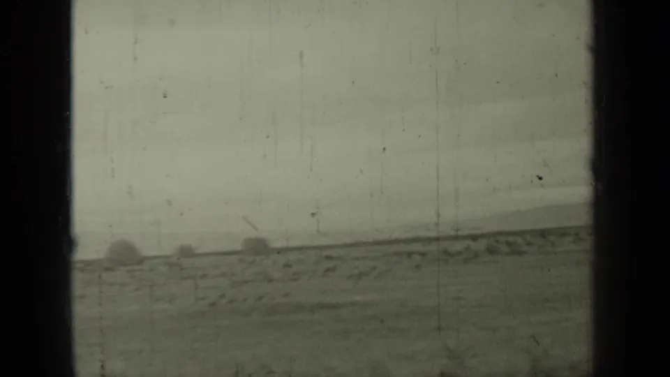 1937 Klamath-area shoreline view from a moving vehicle, with calm water, low land, and open ground under a hazy sky.