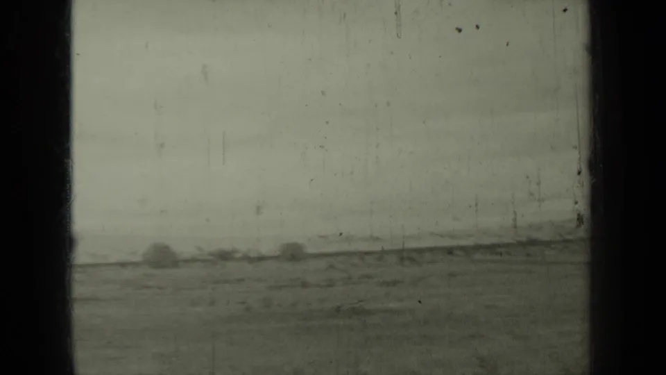 1937 Klamath-area waterside view with a faint shoreline, open foreground, dark window bars, and visible 8mm film wear.