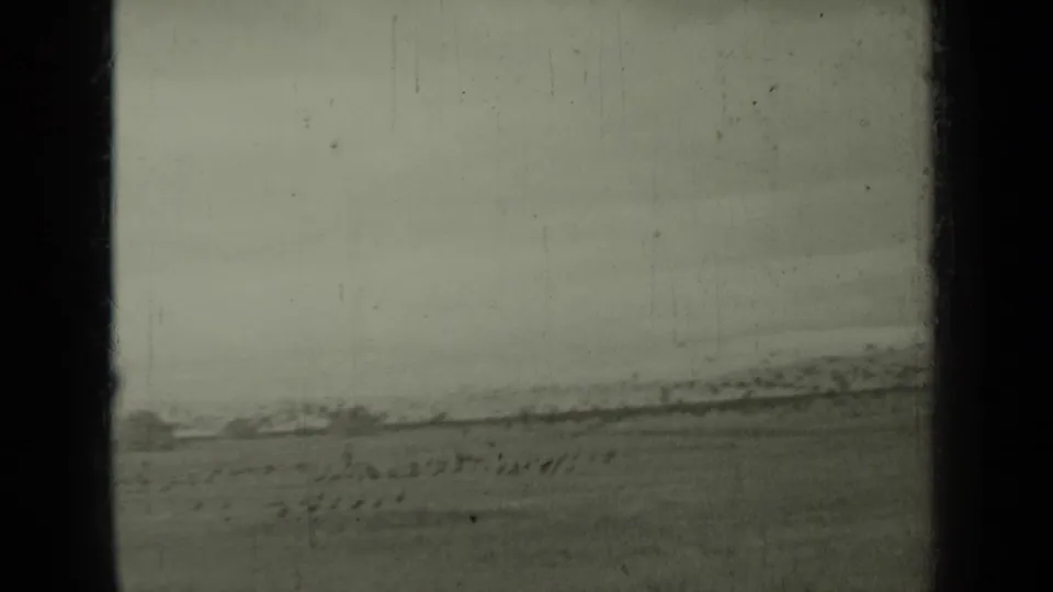 1937 Klamath, California 8mm frame showing an open field, low horizon, and indistinct distant shapes beneath an overcast sky.