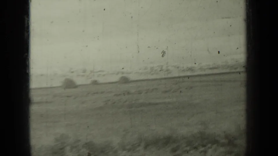 1937 Klamath, California home-movie frame with a rural horizon, scattered dark forms, and a prominent vertical film-frame divider.