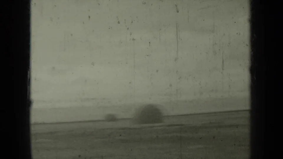 1937 Klamath, California frame showing a broad open field, hazy horizon, and a larger indistinct dark form near the right side.