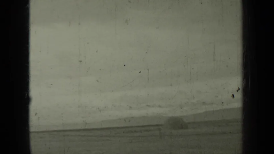1937 Klamath, California 8mm frame showing railroad tracks, hills, and a distant steam train in a soft monochrome landscape.