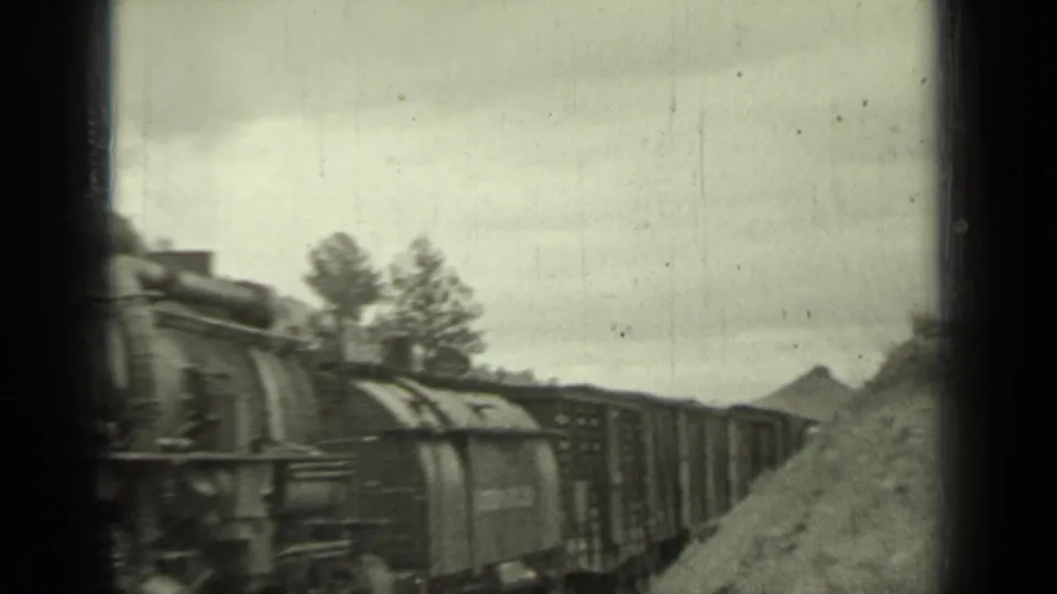 Steam engine and freight cars move along a hillside rail line in the supplied 1937 Klamath, California footage.