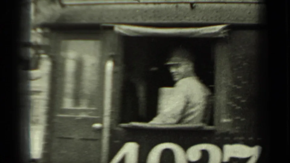 A locomotive crew member is visible in the cab as the engine passes, with large numerals on the side.