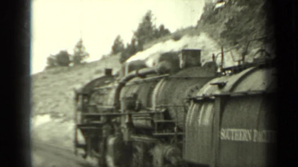 Southern Pacific steam train appears to pass through a rural Klamath, California landscape with smoke and hillside behind it.