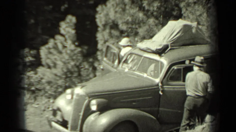 A rounded 1930s automobile with a canvas-covered roof appears parked on a dirt path in the supplied Klamath, California footage.