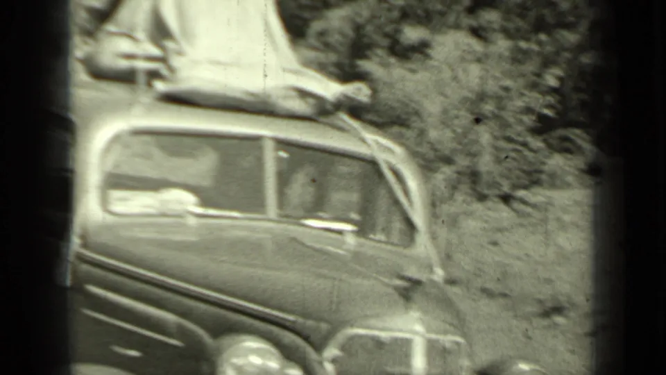 A 1930s sedan sits near a wooded roadside in Klamath, California, with canvas or tenting tied across the roof.