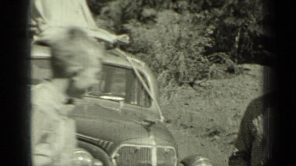 A blurred figure moves past the 1930s sedan in the wooded Klamath roadside scene.