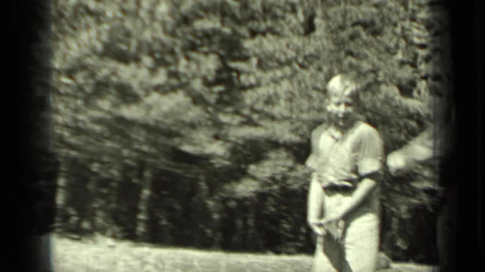 A light-clothed boy stands in a wooded Klamath clearing, holding a small object consistent with the BB gun subject in the clip metadata.