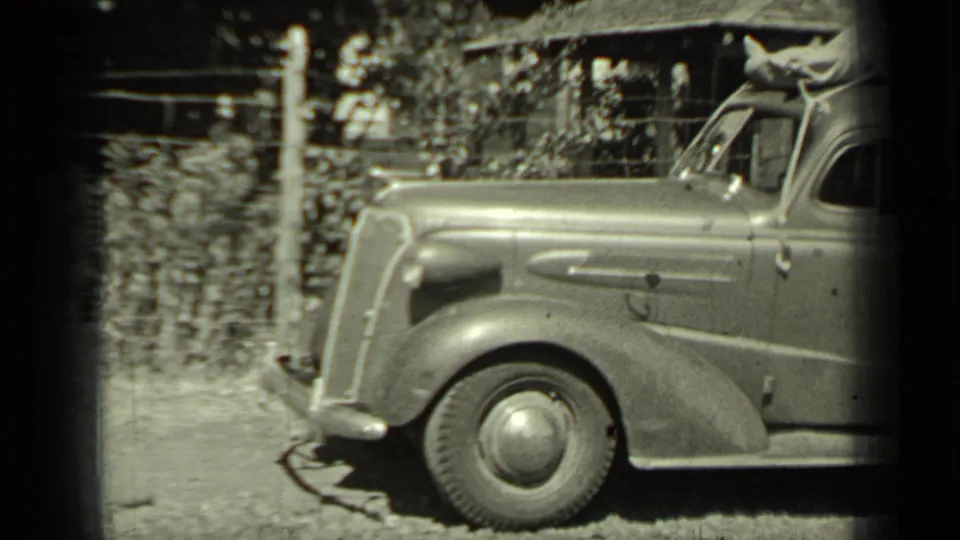 A 1937 Klamath, California home-movie still shows the side and front wheel of a vintage car on a dirt roadside.
