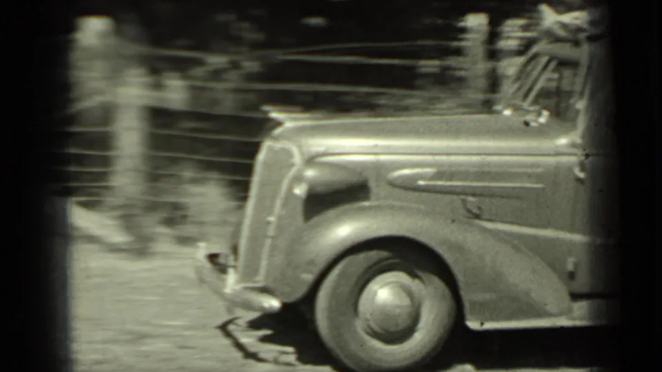 A 1930s-era car appears in profile while moving past a roadside area in Klamath, California.
