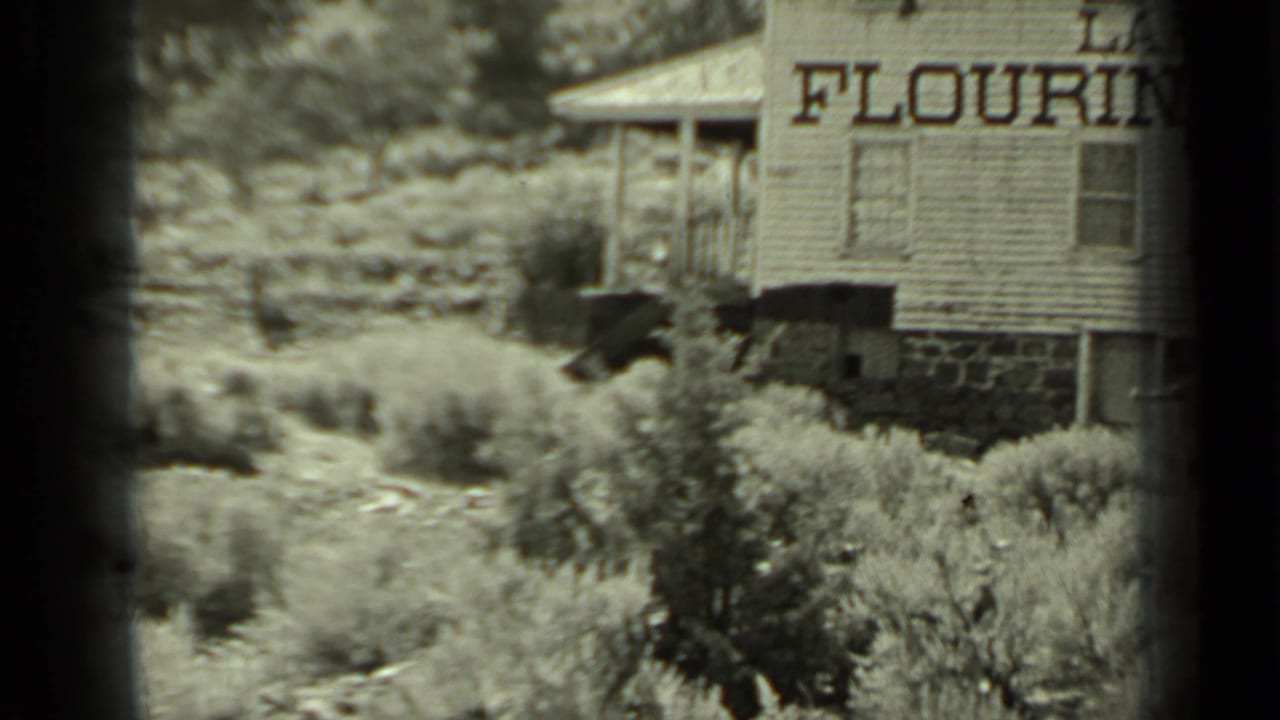 Two adults near brush and a wooden building with partial "FLOURING" lettering.