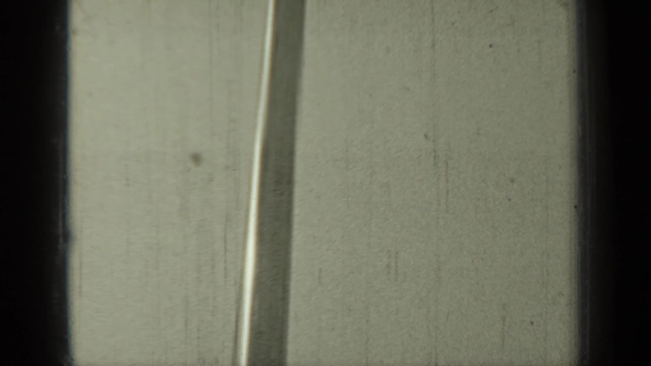 Tall mast or pole against a pale exterior surface, with dark film-edge borders.