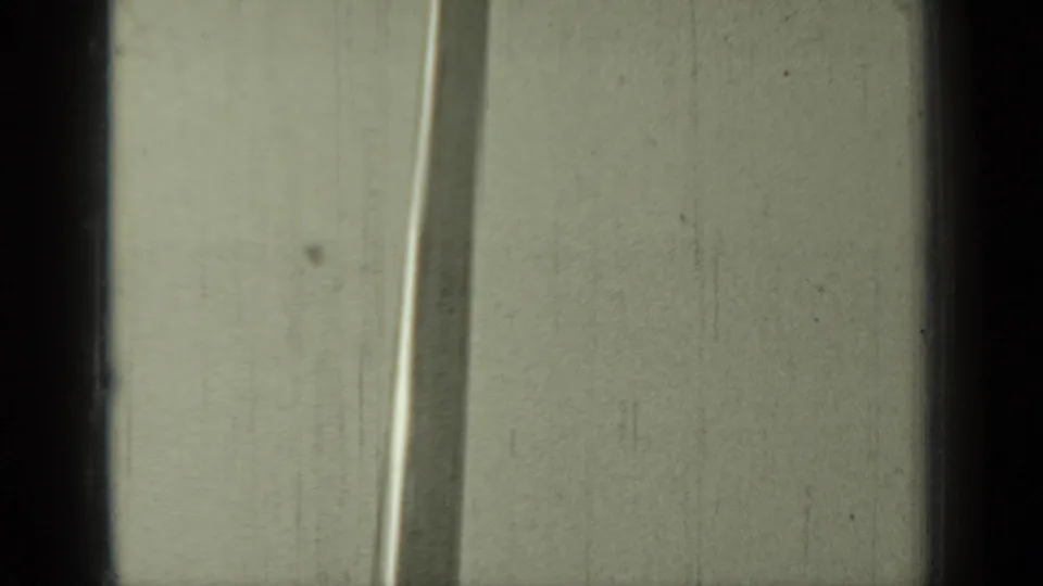 A tall mast or pole seen in soft 8mm footage, likely from the 1937 Klamath, California clip, framed tightly against a pale building or sky.