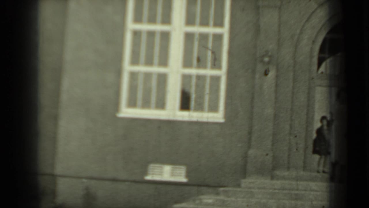 A dark-clothed person stands near an arched doorway beside a large window.