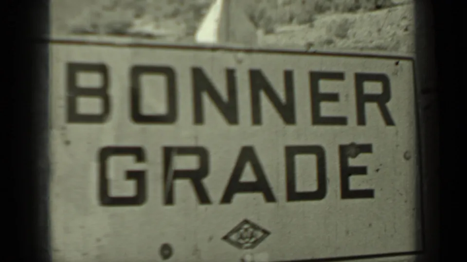 1937 Klamath, California frame with a large Bonner Grade sign filmed close-up against a rugged roadside slope.