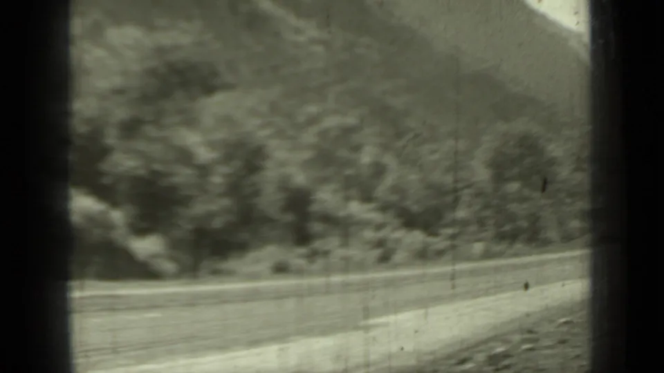 1937 Klamath, California road view showing a curving mountain route through tree-covered hills from a vehicle-side perspective.