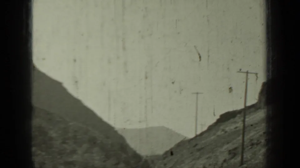 Mountain road near Klamath, California, with utility poles and rocky slopes in a soft monochrome 8mm frame.