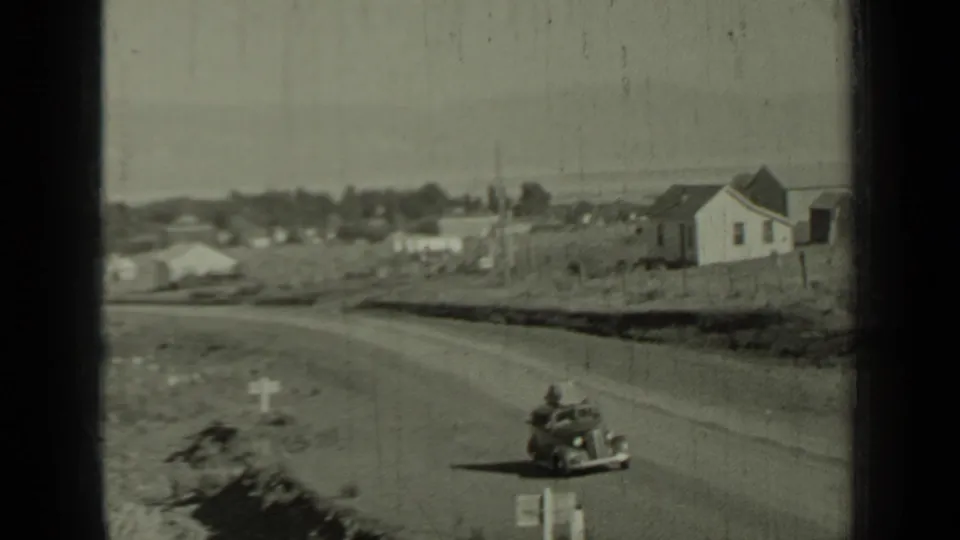 1937 Klamath, California town approach with roadside houses, open lots, and a small vehicle on the road.
