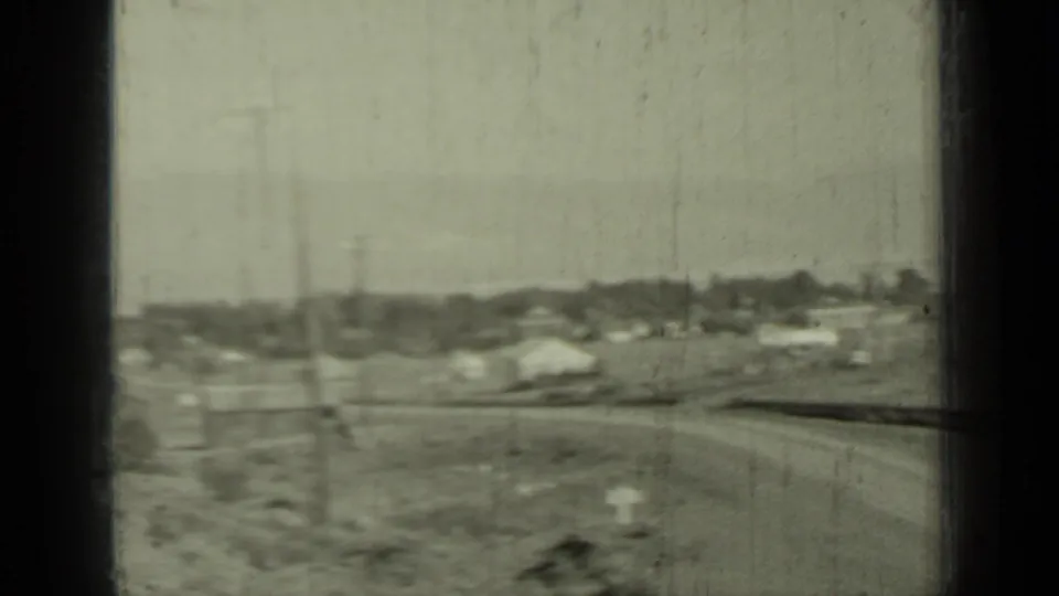 Moving 8mm view of the Klamath, California roadside with distant houses, poles, and open valley ground.