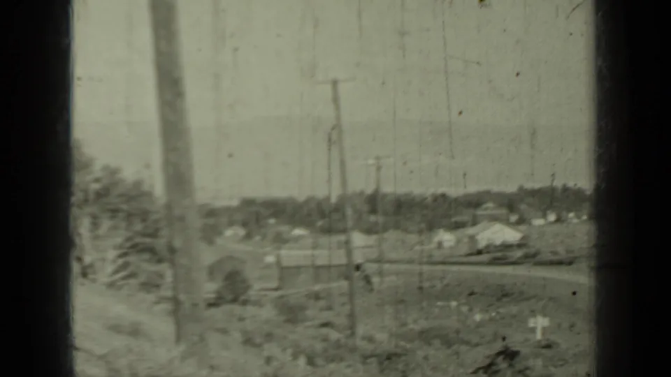 1937 Klamath, California home-movie frame showing a rural road area with utility poles, scattered buildings, and open landscape.