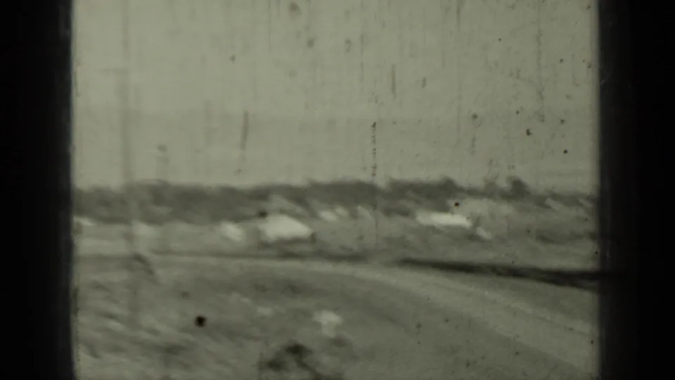 Soft 8mm view of an open Klamath roadside landscape with a dirt road, low buildings, brush, and distant tree line.