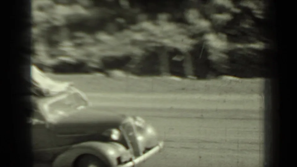 A vintage automobile passes through the frame on a Klamath, California road, softened by motion blur in the 8mm home-movie scan.