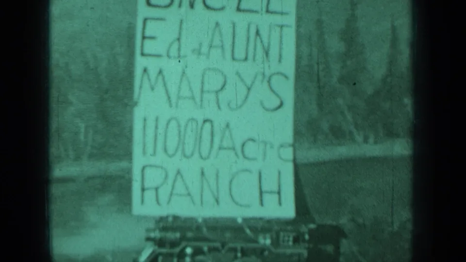 1937 Medford, Oregon home-movie frame showing a hand-lettered Uncle Ed and Aunt Mary's 11,000 acre ranch sign above parked cars.
