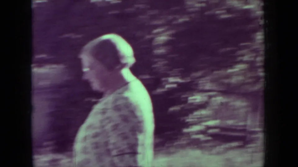 An older woman in profile walks through the yard, with dark foliage and 8mm color fading visible in the Medford 1937 footage.